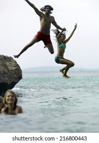 Young Couple Holding Hands And Jumping In Water