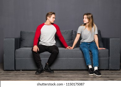 Young couple holding hands but look each other while sitting on sofa - Shutterstock ID 1150175087