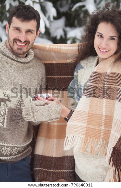 young couple\
holding a hot tea in winter park. Couple hands in mittens take a\
mugs with hot tea in winter\
forest