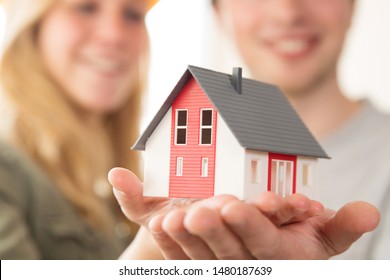 A Young Couple Is Holding A Model House In Hand, New Home