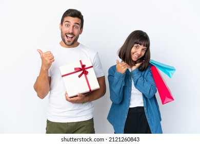 Young Couple Holding Shopping Bags And Present Isolated On White Background Giving A Thumbs Up Gesture With Both Hands And Smiling