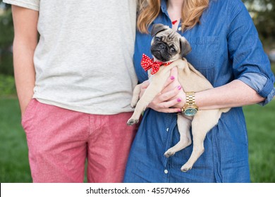 Young Couple Holds Small Pug Puppy Outside