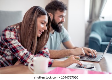 Young couple at home paying bills with laptop.