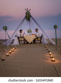 Young Couple Honeymoon Dinner By Candle Light During Sunset On The Beach, Men And Woman Having Dinner On The Beach Romantic Setting In Thailand During Sunset Pattaya