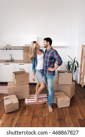 Young Couple Hugging In New Kitchen With Boxes With Home Things.Copy Space