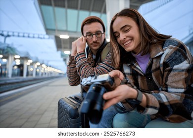 A young couple immersed in conversation while reviewing photos on a camera, enjoying a relaxed moment during their travels. - Powered by Shutterstock