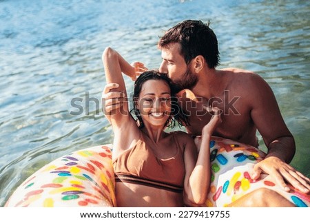 Young couple with inflatable rings having fun at the sea on summer vacation.