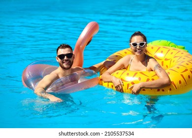 Young couple with inflatable rings in swimming pool - Powered by Shutterstock