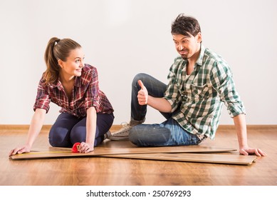 Young couple are installing laminate flooring in the room.