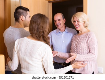 young couple inviting elderly parents to come inside