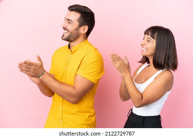 Young couple isolated on pink background applauding after presentation in a conference - Powered by Shutterstock