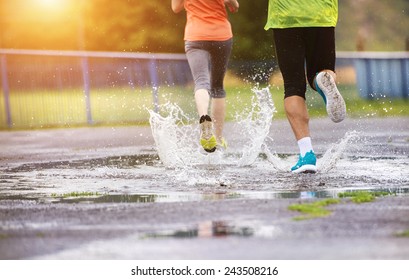Young couple jogging on asphalt in rainy weather