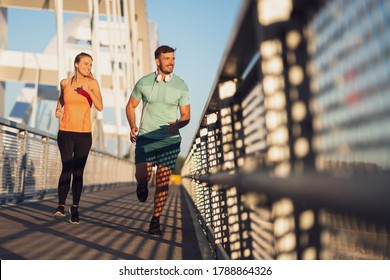 Young couple is jogging outdoor on bridge in the city. - Powered by Shutterstock