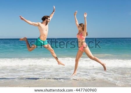 Young couple jumping on beach