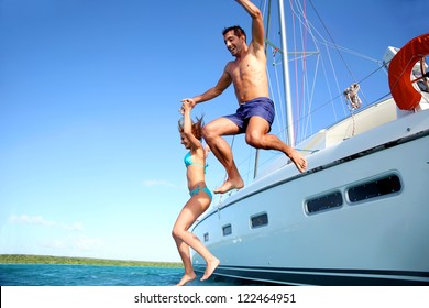 Young Couple Jumping In Water From Yacht