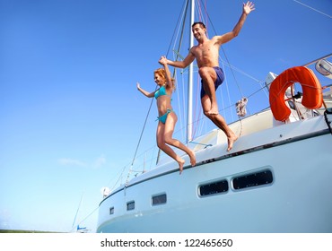 Young Couple Jumping In Water From Yacht