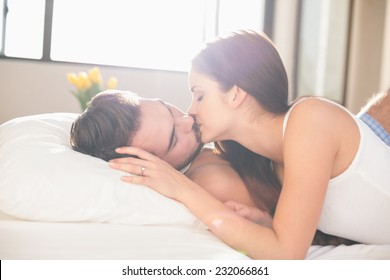 Young Couple Kissing In Bed At Home In Bedroom