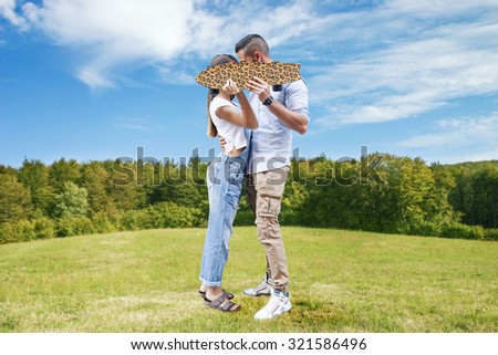 young couple kissing hiding behind a skateboard