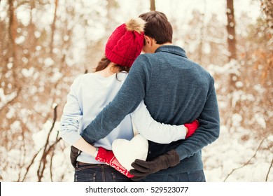 Young Couple Kissing And Holding Snow Heart