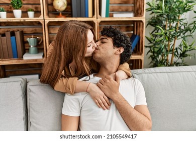 Young Couple Kissing And Hugging Sitting On The Sofa At Home.