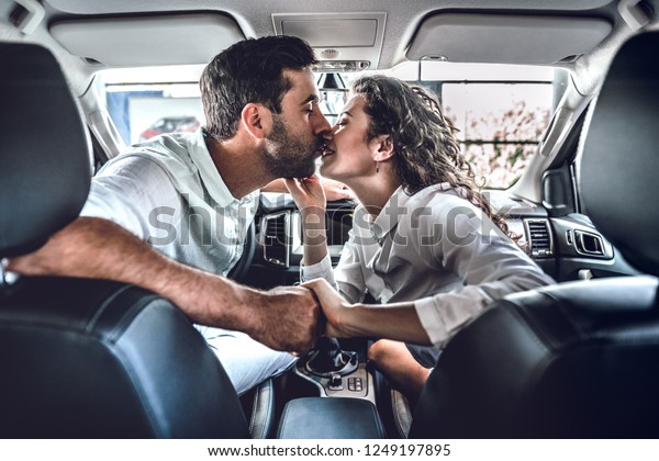 Young couple kissing in new car. Two young people\
buying new car