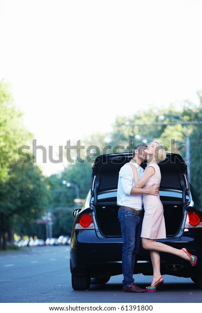 A young\
couple kissing on the background of\
auto