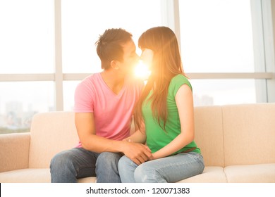 Young Couple Kissing On Sofa With Sunset In The Background