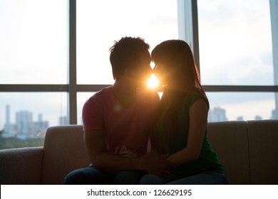 Young Couple Kissing On Sofa With Sunset In The Background