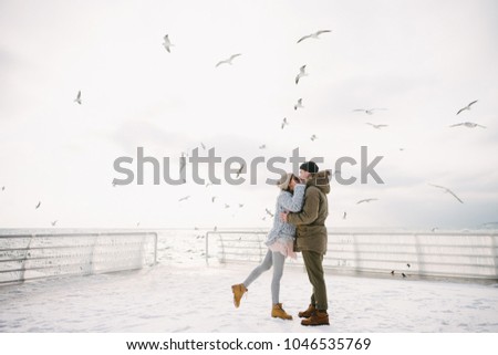 young couple kissing on winter quay with seagulls