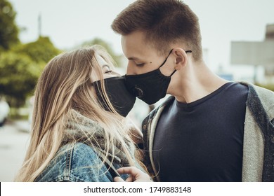 Young couple kissing in protective black masks. Pandemic. Coronavirus. A guy and a girl kiss through a medical mask. Covid 19. Summer 2020. Kiss.