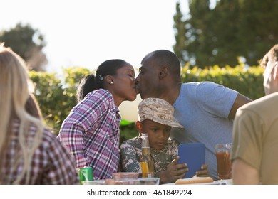 Young Couple Kissing At Soldier's Homecoming Party