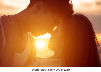 young couple kissing at sunset on beach