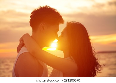 young couple  kissing at sunset on beach