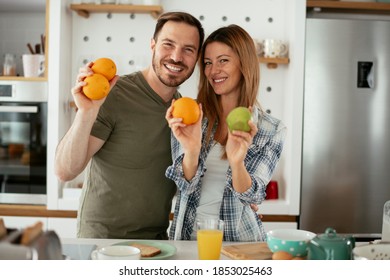 Young Couple In Kitchen. Happy Couple Is Making A Fruit Salad.