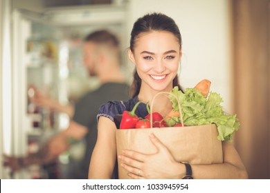 Young couple in the kitchen , woman with a bag of groceries shopping - Powered by Shutterstock