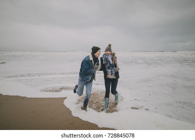 A Young Couple Laugh And Paddle In The Sea On A Winter Beach.