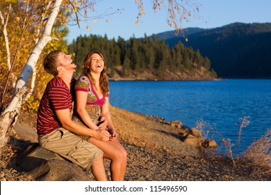 Young Couple Laughing And Having A Good Time By The Lake