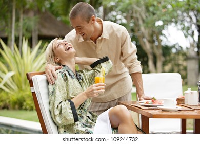 Young couple laughing while having a luxury breakfast in a tropical garden while on vacations. - Powered by Shutterstock