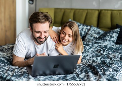 Junge Paare lachen beim Anschauen von Medien auf einem Laptop zu Hause