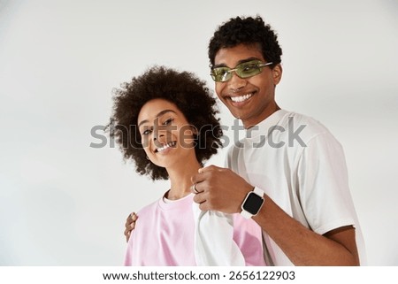 A young couple laughs while playfully posing together, showcasing their unique style and bond.
