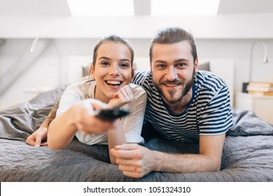 Young couple laying in the bed and watching tv