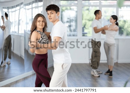 Young couple learns to tango pair dance during dance class in studio, repeat movements and learn wedding dance. Studio school for amateur and professional dancers