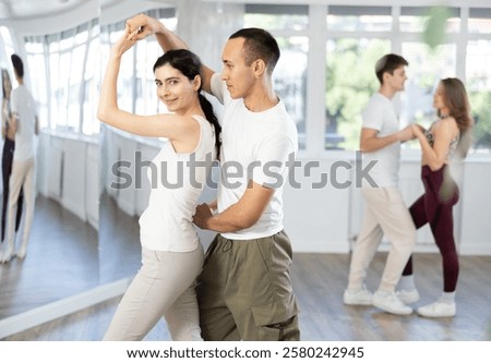 Young couple learns to tango pair dance during dance class in studio, repeat movements and learn wedding dance. Studio school for amateur and professional dancers