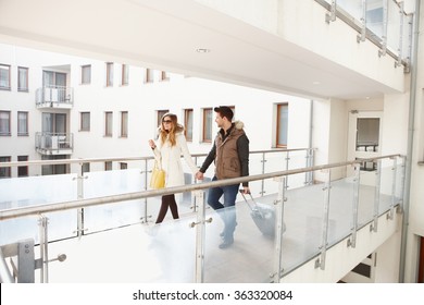 Young Couple Leaving Apartment House With Small Luggage Hand In Hand.