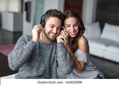 Young Couple Listening Music Indoors, Sharing Headphones