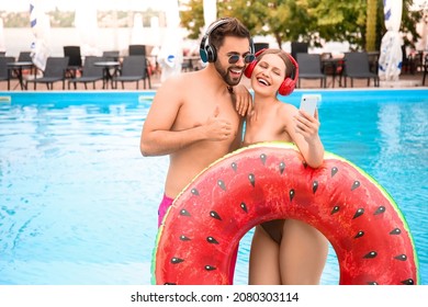 Young couple listening to music and taking selfie near swimming pool - Powered by Shutterstock