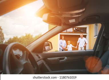 Young Couple With Little Boy Son Goes To Their Car Standing On The Home Yard Inside Car View