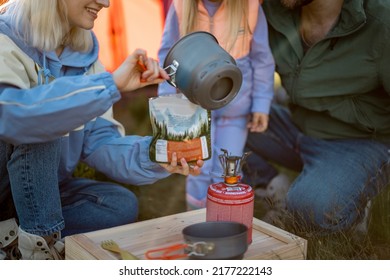 Young Couple With Little Girl Cooking Dried-food For Hiking, Pouring Boiling Water Into The Package. Family At Campsite Making Food For Travelers. Sublimated Food And Family Camping Concept