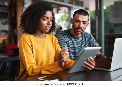 Young Couple Looking At Digital Tablet In Cafe