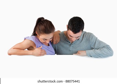 Young Couple Looking Down A Wall Against A White Background